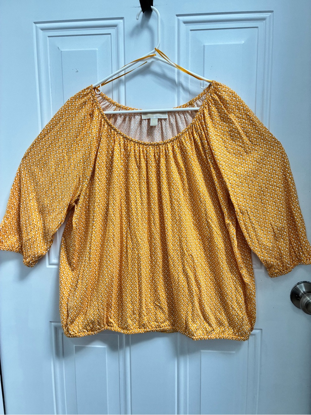 Michael Kors 3/4-sleeve blouse with a scoopline neck and bubble hem.
